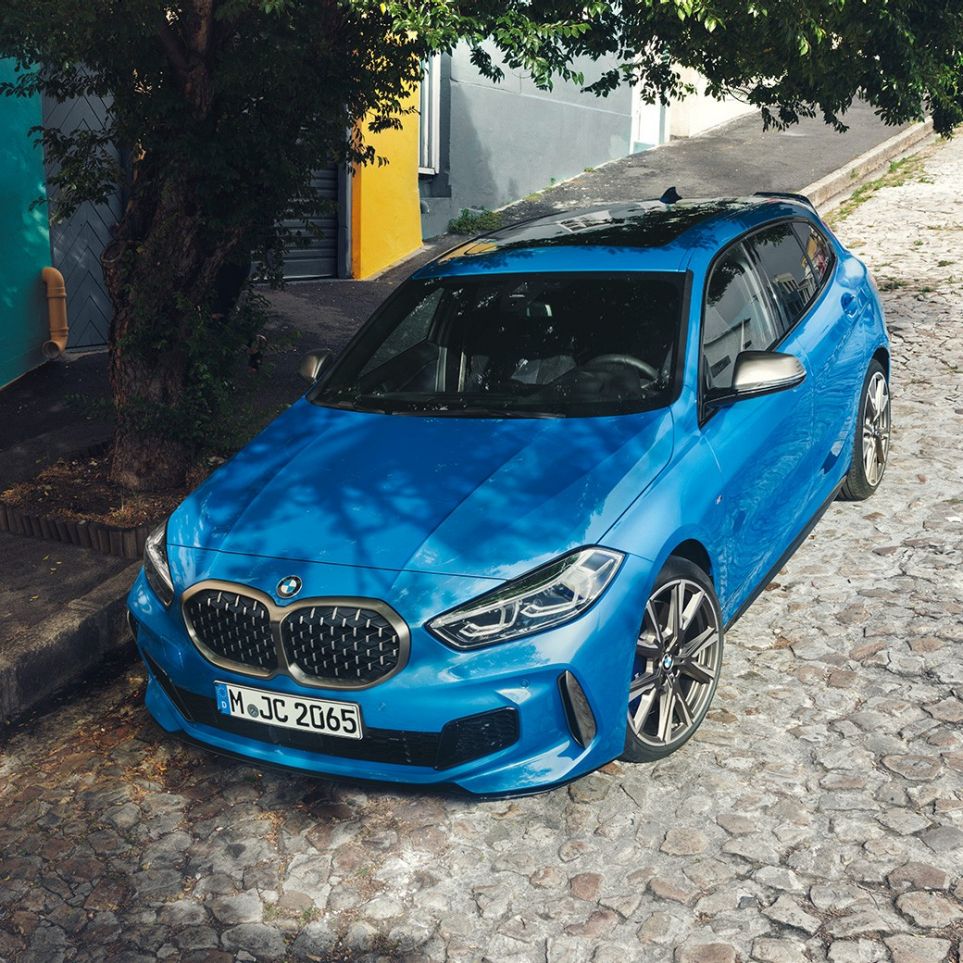 1 Series BMW at the roadside. 1 Series BMW in Misano Blue metallic, three-quarter front view, parking at the roadside from a bird’s eye view.