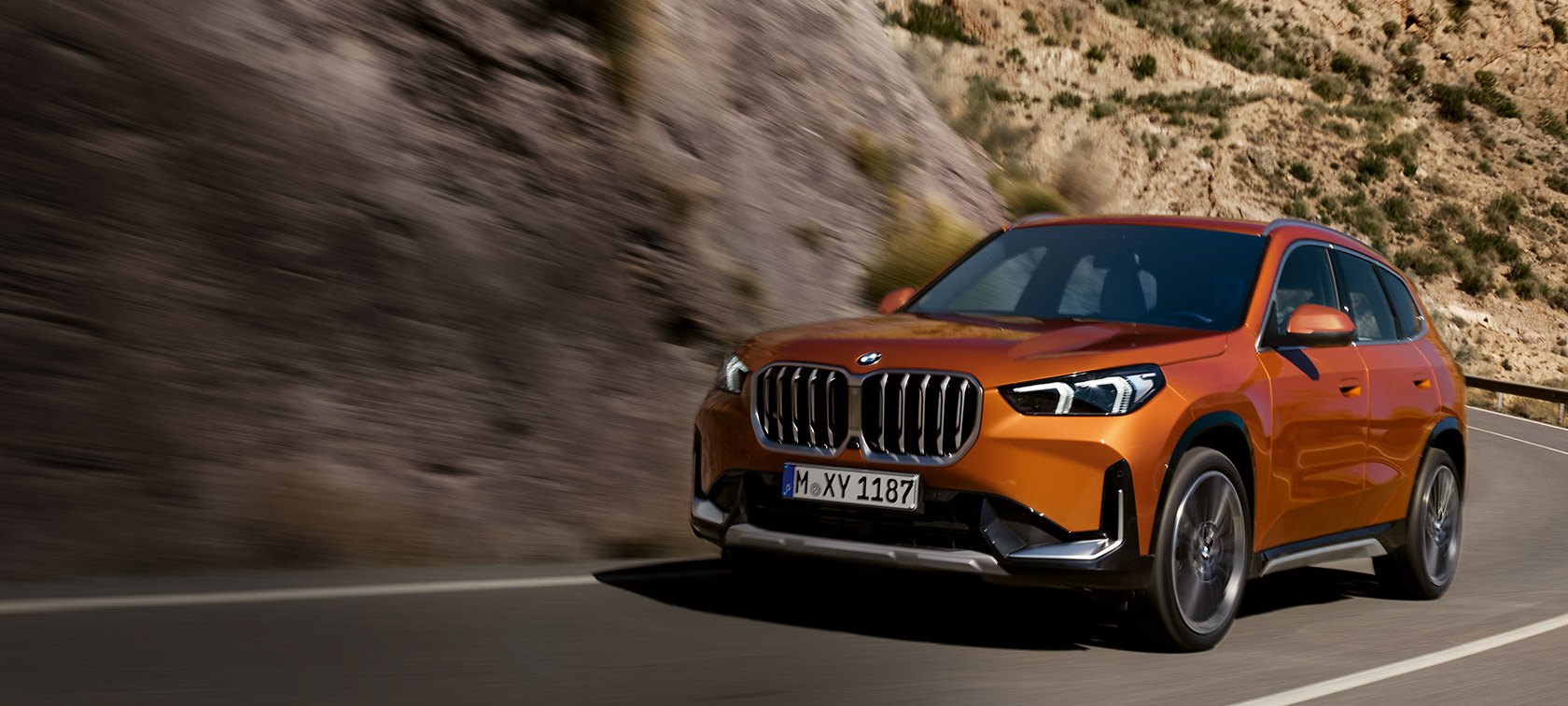 BMW X1 U11 xLine Utah портокалова металик тричетвртински поглед однапред во возење по регионален пат